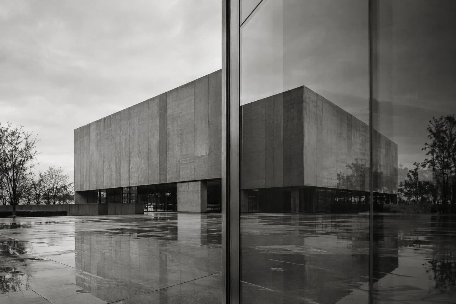 Monochrome photograph of a concrete building reflected in adjacent glass panels